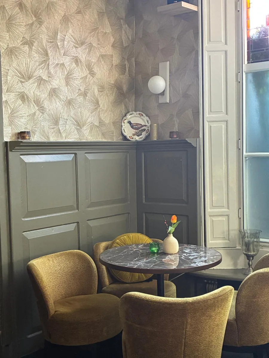 Ronde marmeren tafel met goudkleurige fauteuils bij het raam van Tante Es